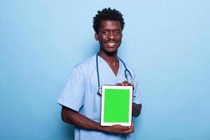 homem enfermeira mostrando tela verde vertical no tablet foto