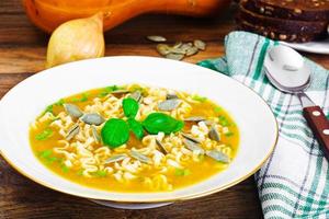 sopa de abóbora com macarrão, verduras e sementes de abóbora foto