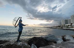 garota na praia perto das rochas com um guarda-chuva em dia nublado foto