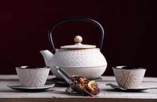 bule de porcelana branca e dois copos para servir o chá com palin de especiarias foto