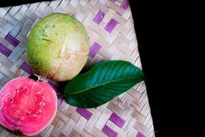 goiaba isolado. coleção do vermelho carnudo goiaba fruta com amarelado verde pele e folhas isolado em Preto fundo com tecido bambu. foto