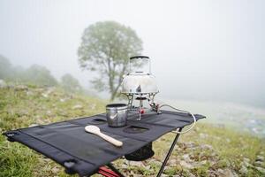 fechar-se do caminhada engrenagem, acampamento conceito dentro a montanhas cozinha dentro natureza, ferver água em uma caminhada queimador, Preto acampamento mesa foto