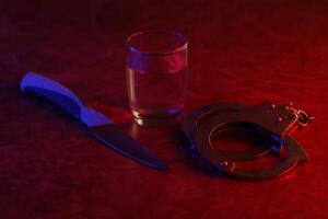 vidro com vodka álcool bebida, faca e algemas. conceito do alcoolismo, Criminoso foto