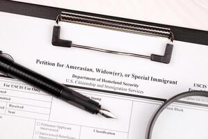 i-360 petição para amerasiático, viúvo ou especial imigrante em branco Formato em a4 tábua mentiras em escritório mesa com caneta e ampliação vidro foto