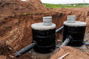 séptico tanque esgoto é cavado dentro a chão, reforçado concreto bem dois peças, hidráulico instalação, suburbano construção, encanamento trabalhar, gasoduto dentro a chão. foto