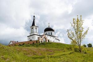 a Igreja do a arcanjo Michael a cidade do birsk Rússia bascortostão, a ortodoxo têmpora, uma mosteiro carrinhos em uma montanha, uma tijolo fortaleza parede, uma branco igreja. foto