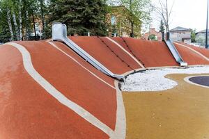 a cidade diversão parque é uma crianças Parque infantil com uma montanha, brilhante suave slides para crianças, uma borracha estrada superfície, uma seguro Parque infantil para crianças. foto