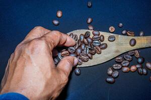 Preto café feijões estão visto fechar acima com uma de madeira colher em uma Preto pano. foto