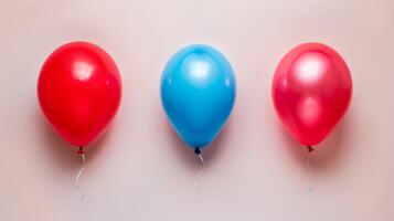 três colorida balões dentro vermelho e azul flutuando contra uma Rosa pastel fundo para festa celebração foto