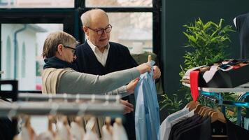 Senior casal compras para formal agasalhos às moda butique, olhando para na moda elegante roupas Itens para crio Novo roupas para idosos cara. pessoas procurando para à moda mercadoria. Câmera uma. foto