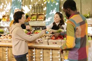 sorridente amigáveis comerciante oferta cliente para gosto variedades do fresco sazonal maçãs às Comida mercado. feliz fêmea agricultor vendendo local caseiro orgânico frutas e legumes. foto