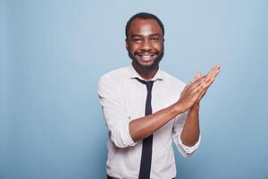 sorridente masculino adulto palmas mãos e torcendo em trabalho bem feito, desfrutando uma significativo ganhar. animado Preto homem expressando dele Parabéns com a aplausos gesto e positivo resposta. foto