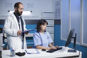 caucasiano médico e cuidados de saúde trabalhador colaborar dentro a escritório. elas usar tecnologia, discutir médico gráficos, e vestem esfrega e laboratório casacos. representa trabalho em equipe e comunicação dentro assistência médica. foto