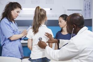 africano americano médico usando estetoscópio para coração checar do uma criança. às clínica consulta sessão, Preto homem médico usando uma médico instrumento para ouço para batimento cardiaco do uma jovem garota. foto