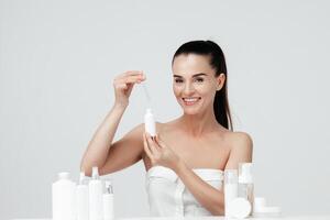 meio envelhecido, maduro mulher mostrando Cosmético produtos branding brincar. diariamente cuidados com a pele e corpo Cuidado rotina. natural Cosmético creme, sérum, branco garrafas embalagem, bio orgânico produtos foto