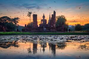 grande Buda às pôr do sol dentro wat Mahathat têmpora, sukhothai histórico parque, tailândia. foto
