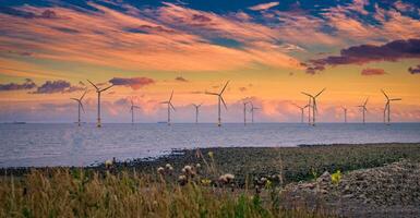 no mar vento turbina dentro uma Parque eólico debaixo construção fora a Inglaterra costa às pôr do sol foto