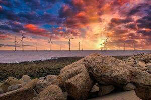 no mar vento turbina dentro uma vento Fazenda debaixo construção fora a Inglaterra costa às pôr do sol foto