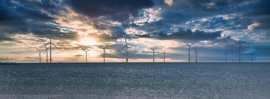 no mar vento turbina dentro uma Parque eólico debaixo construção fora a Inglaterra costa às pôr do sol foto