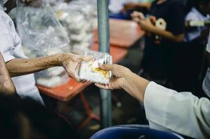 alimentando conceitos . mão oferecido para doar Comida a partir de uma rico homem compartilhar. a conceito do social partilha . pobre pessoas recebendo Comida a partir de doações foto