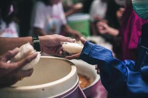 voluntários estão dando livre Comida para Socorro a com fome pobre conceito do Comida partilha foto