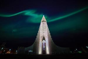 luzes do norte brilhando sobre a igreja em reykjavik foto