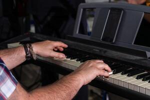 uma fechar-se do uma do homem mãos jogando a elétrico órgão. dele dedos mover rapidamente através a teclado, capturando a foco e precisão requeridos para desempenho. foto