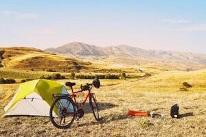 panorama da bicicleta vermelha de turismo descarregada pela tenda verde. conceito de turismo de acampamento e bicicleta viaja pela armênia de bicicleta nas montanhas no outono foto