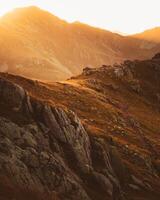 rastreamento estático vista alpinista mochileiro na trilha de rocha negra em lagodekhi desfrutar do pôr do sol dramático sobre a montanha contra o sol foto