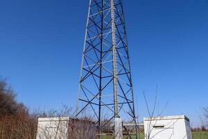 antena elétrica e torre transmissora de comunicação em uma paisagem do norte da Europa contra um céu azul foto