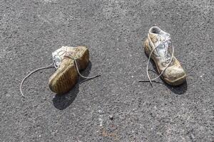 conceito de sapatos velhos deixados em uma estrada de ashpalt com espaço de cópia para texto. foto