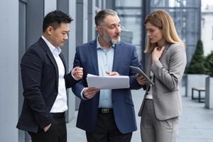 diverso o negócio grupo do três colegas trabalhadores, chateado e desapontado, resultado do financeiro relatório e contrato documento, o negócio trabalhadores lado de fora escritório construção dentro o negócio ternos conversando. foto