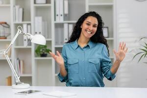 uma preparado profissional mulher gestos enquanto participando dentro uma conferência ligar a partir de uma bem organizado escritório espaço. foto