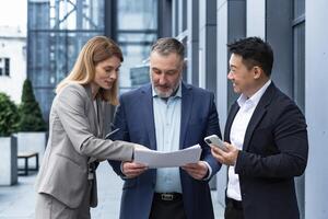 três empresários lado de fora escritório construção com documentos discutindo planos, empresários e empresária tendo Diversão conversando e conversando, diverso o negócio grupo dentro o negócio ternos foto