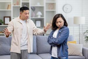 família briga, ásia casal homem e mulher gritando às cada outro, família conflito, asiáticos às casa em pé Bravo dentro vivo sala. foto