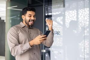 uma homem é segurando uma célula telefone e sorridente foto