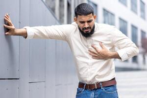 homem dentro dor agarrando peito experimentando de repente coração ataque ao ar livre foto