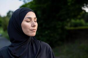 uma muçulmano mulher vestindo uma hijab carrinhos no meio exuberante vegetação, simbolizando serenidade e a conexão entre fé e natureza. foto