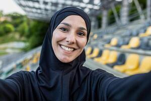 uma confiante atleta às a Esportes estádio captura uma momento do solidão com uma selfie vestindo uma Preto capuz. foto