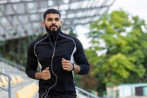 ativo barbudo homem corrida ao ar livre com fones de ouvido foto