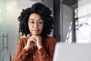 sério pensando mulher trabalhando com computador portátil, digitando em teclado, pensando concentradamente sobre resolução atual problemas, o negócio mulher bem sucedido satisfeito e confiante às local de trabalho dentro escritório. foto