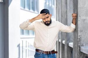 casual vestido homem inclinado em uma concreto parede ao ar livre foto