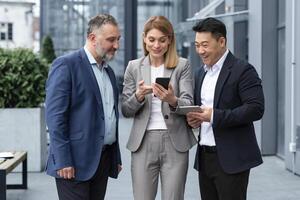 três isto especialistas empreendedores lado de fora escritório construção assistindo em do colega telefone, feliz e sorridente em repouso em pausa a partir de trabalhos foto