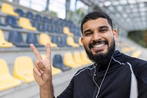 sorridente barbudo homem mostrando Paz placa vestindo roupa de esporte foto