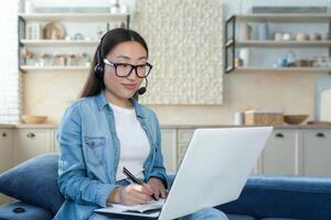 jovem ásia mulher trabalhando a partir de casa remotamente on-line, empresária usando fone de ouvido e computador portátil para chamar, mulher trabalhando dentro tecnologia Apoio, suporte e cliente serviço foto