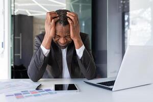 africano americano maduro adulto homem de negocios chateado dentro depressão às ambiente de trabalho, Senior homem trabalhando dentro meio do escritório, infeliz com resultados do financeiro realização banqueiro investidor foto