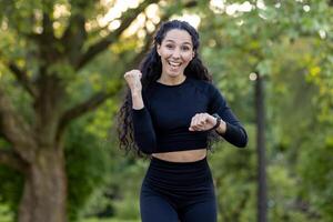 vibrante imagem do uma alegre hispânico mulher corrida dentro uma parque, expressando vitalidade e felicidade. perfeito capturar do ativo estilo de vida e ginástica entusiasmo. foto