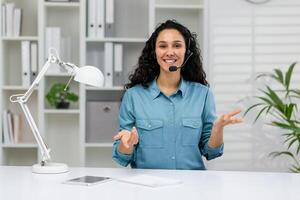 uma alegre cliente serviço representante dentro uma azul camisa e fone de ouvido noivando dinamicamente dentro uma chamar, expressando positividade e profissionalismo dentro uma bem iluminado escritório. foto