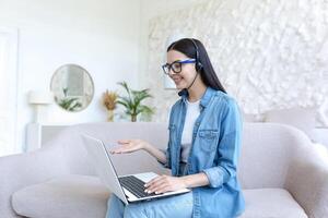 lindo mulher estudando às lar, falando em ligar com professor, usando fone de ouvido foto