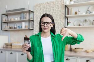 insatisfeito mulher segurando uma Barra do chocolate dentro dela mão e pontos uma dedo do não gostar foto